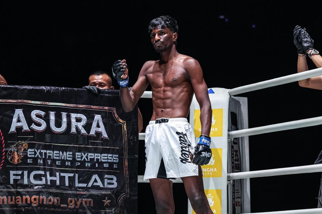 A fighter in white Fairtex shorts stands in the ring corner beside a banner reading Asura, Extreme Express Enterprise, Fightlab.