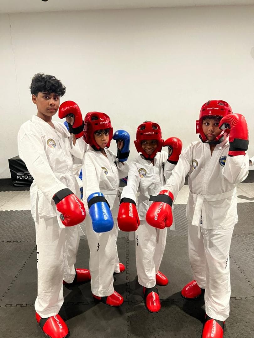 Four young Taekwon-Do students in white uniforms wearing Fightlab gloves, headgear and foot protectors.