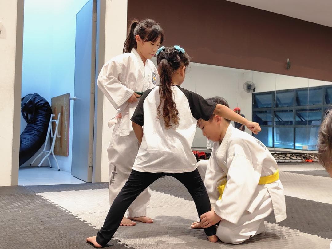 Young Taekwon-Do students practise stances with the help of an older student.