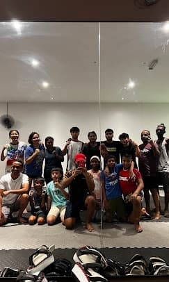A Muay Thai class of adults and kids gathered on the mats for a group mirror selfie at Fightlab.