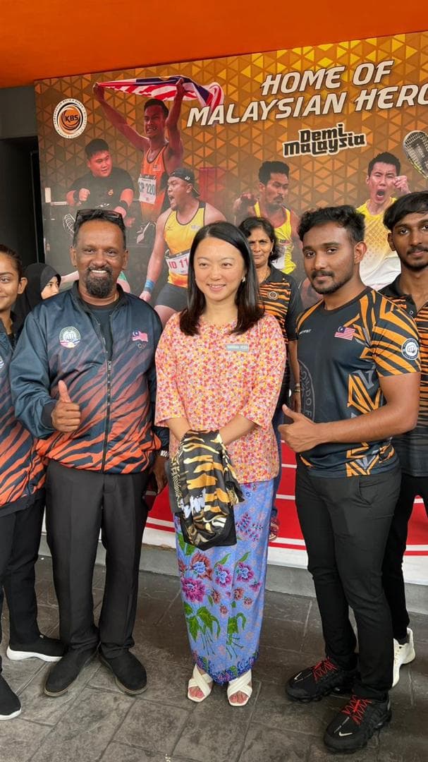 Team members in Malaysia team jackets pose in front of the Home of Malaysian Heroes wall at the National Sports Council.